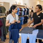 Healthcare professional choosing EPIC by IRG scrub colors and coordinated uniform sets in a medical apparel store